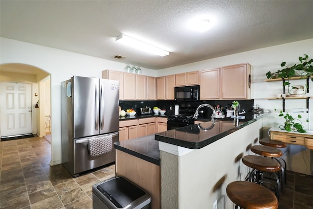 kitchen with a breakfast bar area, visible vents, a peninsula, arched walkways, and black appliances