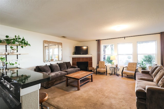 living room with a textured ceiling, a fireplace, visible vents, and light carpet