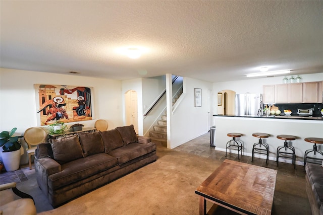 living area with arched walkways, stairway, a textured ceiling, and visible vents