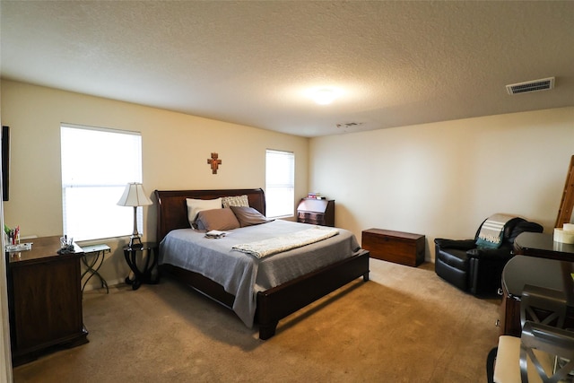 bedroom featuring light colored carpet, visible vents, and a textured ceiling