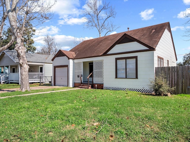 view of front of home featuring a garage, covered porch, fence, and a front lawn