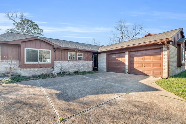 single story home with a garage, brick siding, a shingled roof, concrete driveway, and board and batten siding