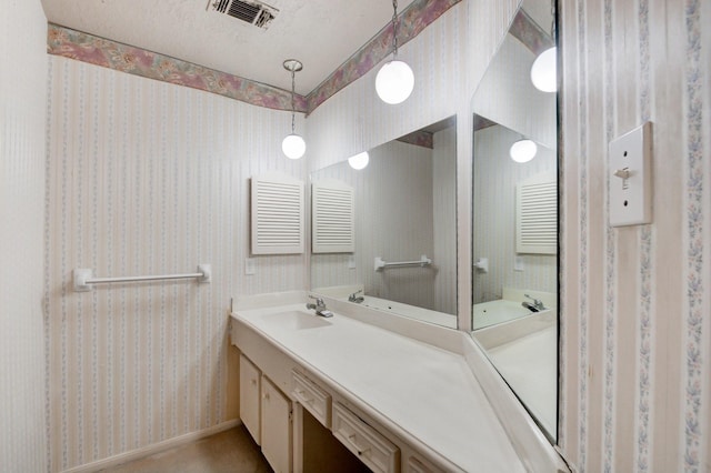 bathroom with wallpapered walls, baseboards, visible vents, a textured ceiling, and vanity