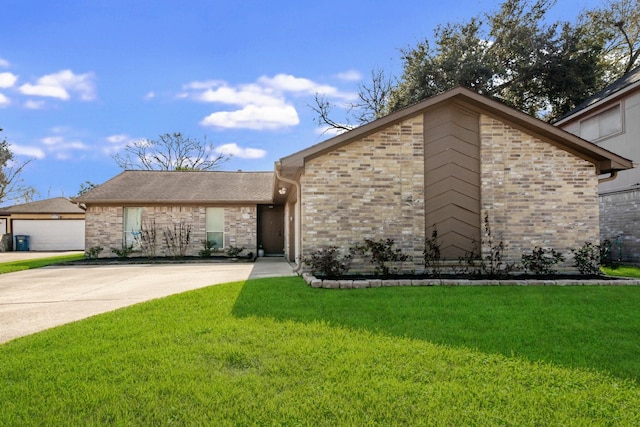 view of front of home featuring brick siding, concrete driveway, and a front yard