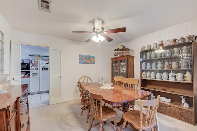 dining area featuring ceiling fan, visible vents, and light colored carpet