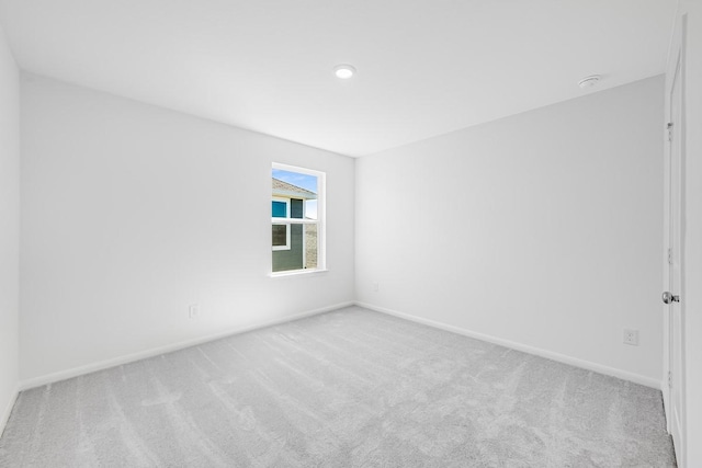 unfurnished room with light carpet and baseboards