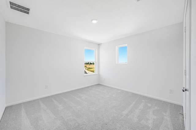 carpeted empty room featuring baseboards and visible vents