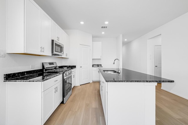 kitchen featuring visible vents, stainless steel appliances, light wood-style floors, and a sink