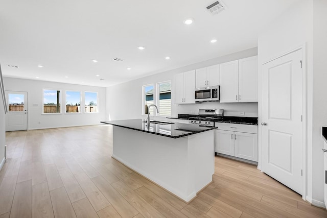 kitchen with light wood-style floors, dark countertops, appliances with stainless steel finishes, and visible vents