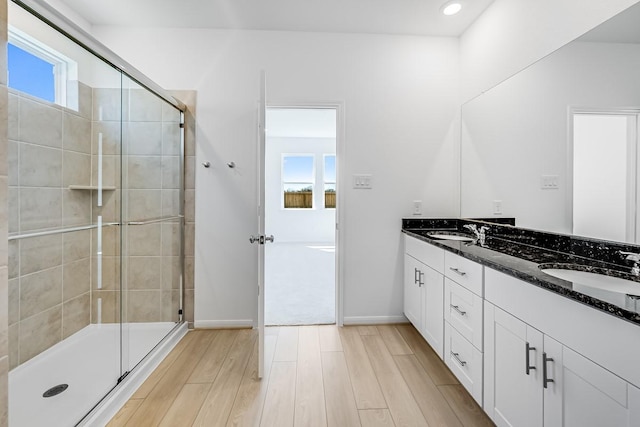 bathroom featuring a stall shower, wood finished floors, baseboards, and a sink