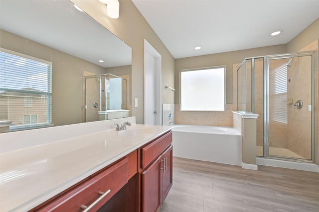 full bathroom with a wealth of natural light, a garden tub, vanity, and wood finished floors