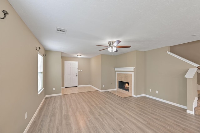 unfurnished living room with light wood finished floors, a fireplace, visible vents, and baseboards