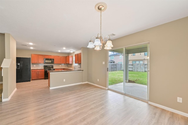 kitchen featuring light wood-style flooring, a notable chandelier, a peninsula, black appliances, and decorative light fixtures