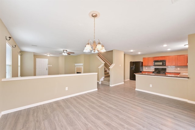 unfurnished living room featuring recessed lighting, stairway, light wood-style floors, baseboards, and ceiling fan with notable chandelier