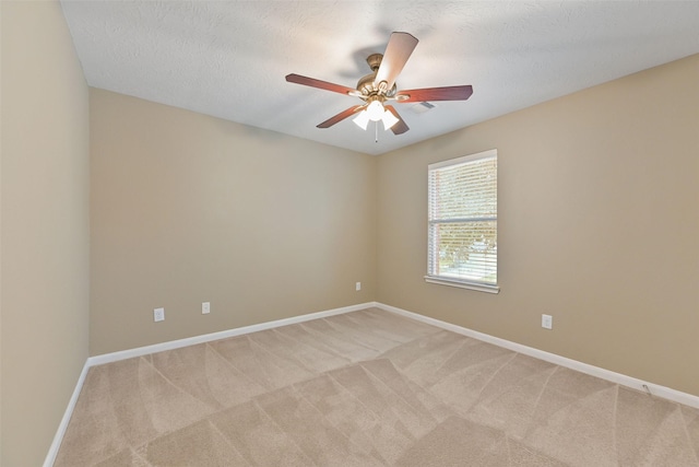 unfurnished room with light colored carpet, ceiling fan, a textured ceiling, and baseboards