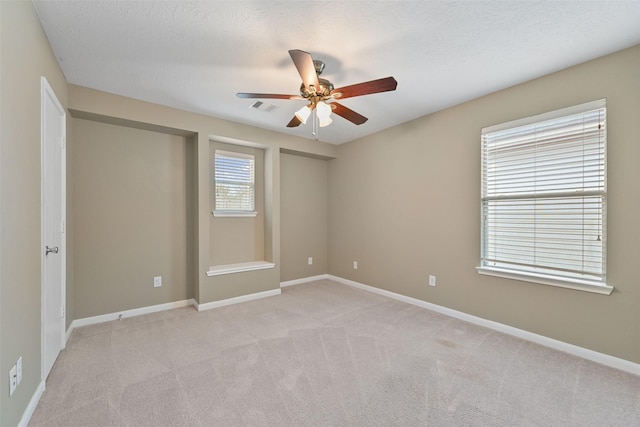 unfurnished room featuring light carpet, a ceiling fan, visible vents, and baseboards