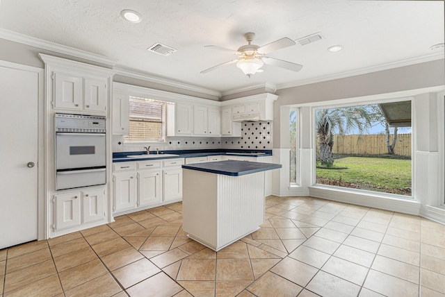 kitchen featuring visible vents, dark countertops, oven, white cabinetry, and a warming drawer