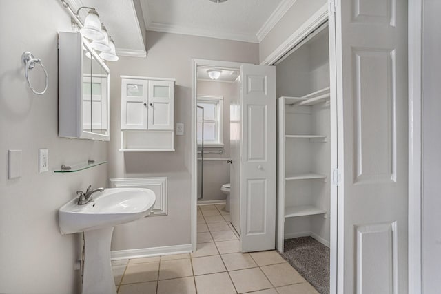 bathroom featuring baseboards, toilet, ornamental molding, tile patterned floors, and a closet