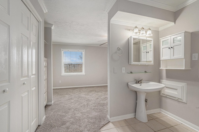 bathroom with tile patterned flooring, crown molding, a textured ceiling, and baseboards