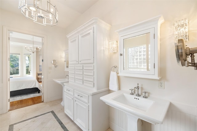 bathroom with two sinks, ensuite bath, and an inviting chandelier