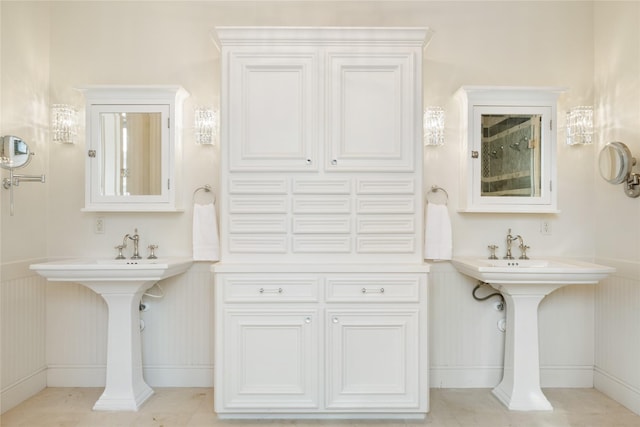 bathroom featuring a wainscoted wall, two sinks, and tile patterned floors