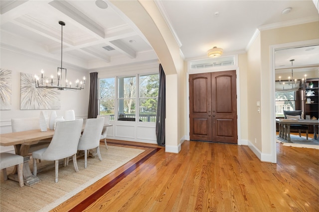 entrance foyer featuring coffered ceiling, ornamental molding, beamed ceiling, light wood-type flooring, and a notable chandelier