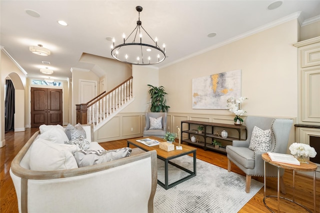 living room with ornamental molding, light wood-style flooring, and stairway