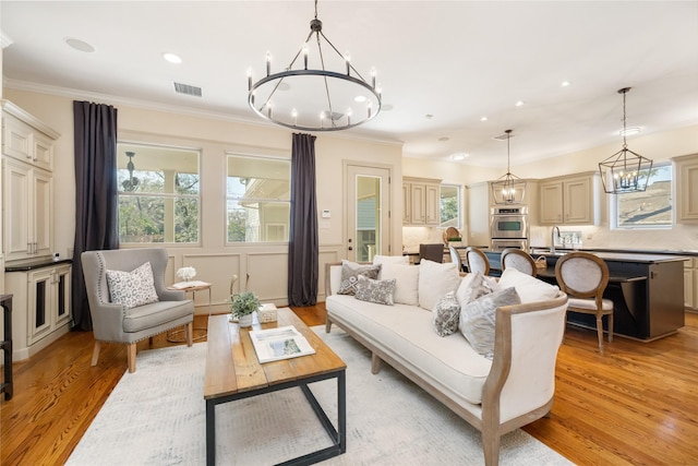 living room with recessed lighting, visible vents, light wood-type flooring, an inviting chandelier, and crown molding