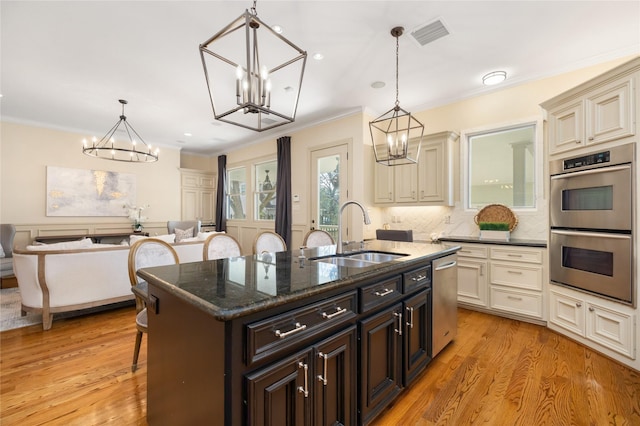 kitchen featuring a breakfast bar area, a sink, a center island with sink, and decorative light fixtures