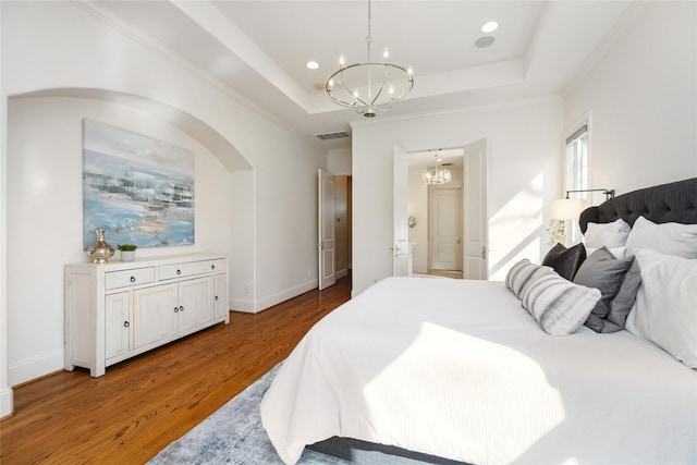 bedroom featuring a tray ceiling, a notable chandelier, recessed lighting, and wood finished floors