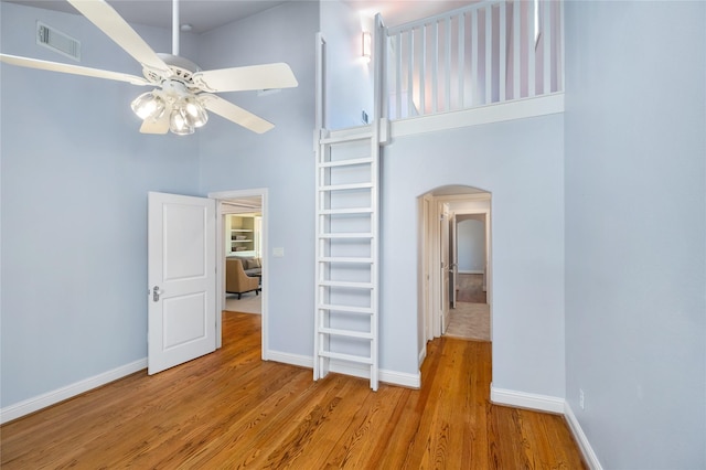 interior space featuring arched walkways, light wood finished floors, visible vents, a high ceiling, and a ceiling fan