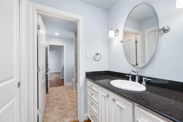 bathroom with toilet, tile patterned floors, baseboards, and vanity