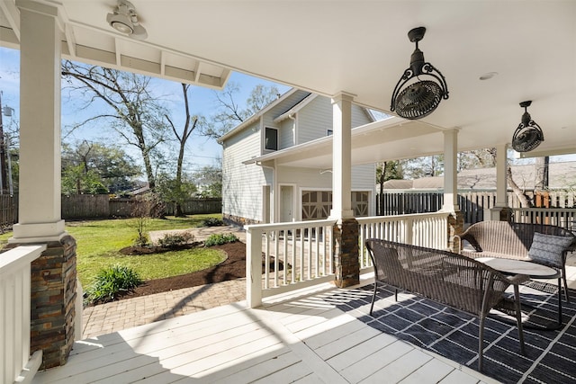 deck with a fenced backyard, a lawn, and a ceiling fan