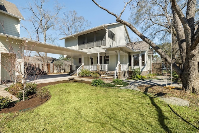 rear view of house featuring covered porch, a lawn, and fence