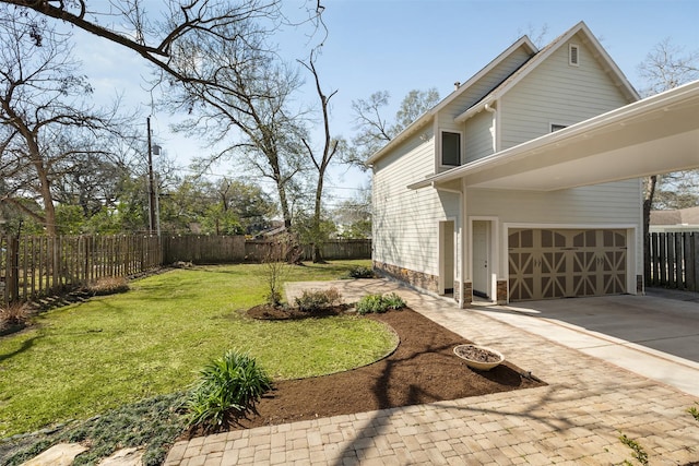 view of yard with an attached garage, fence, and concrete driveway