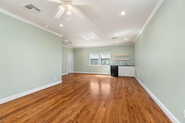 unfurnished living room with ornamental molding, light wood-style floors, visible vents, and baseboards