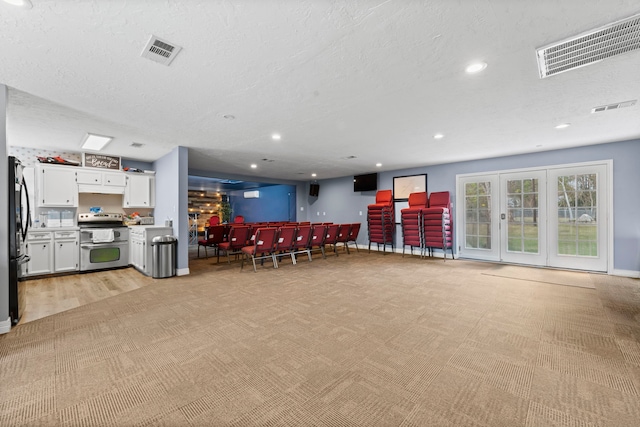 interior space with range with two ovens, visible vents, white cabinets, and open floor plan