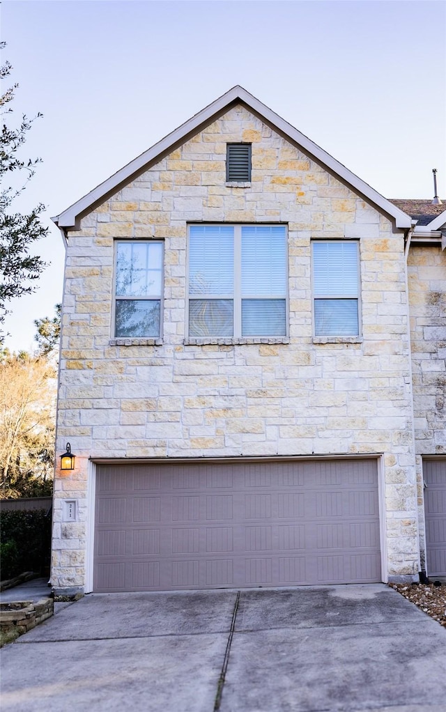 view of home's exterior featuring driveway, stone siding, and an attached garage