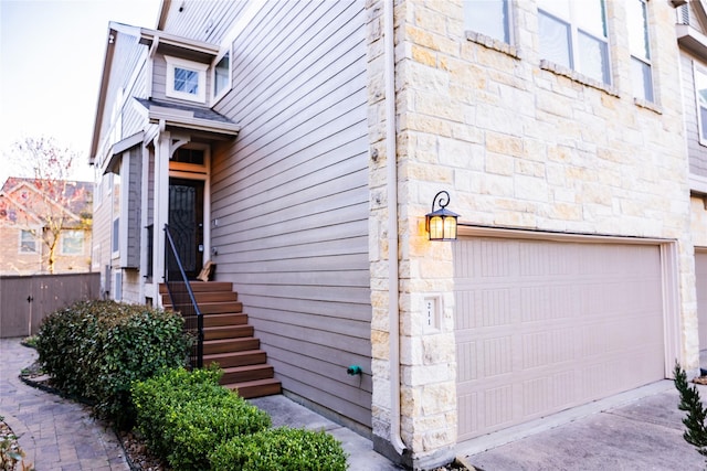 doorway to property featuring a garage and stone siding