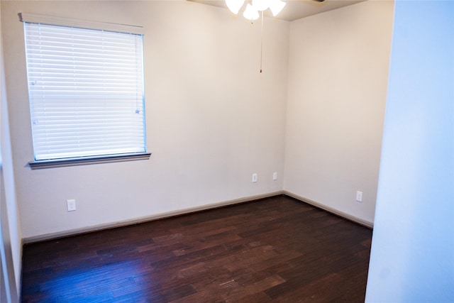 spare room featuring dark wood-style flooring, ceiling fan, and baseboards