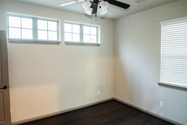 spare room with ceiling fan, visible vents, baseboards, and dark wood-style flooring