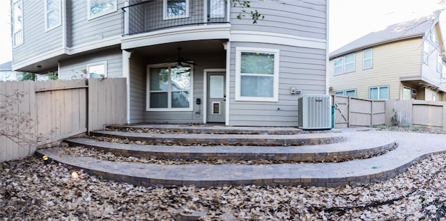 view of exterior entry featuring cooling unit, a ceiling fan, and fence