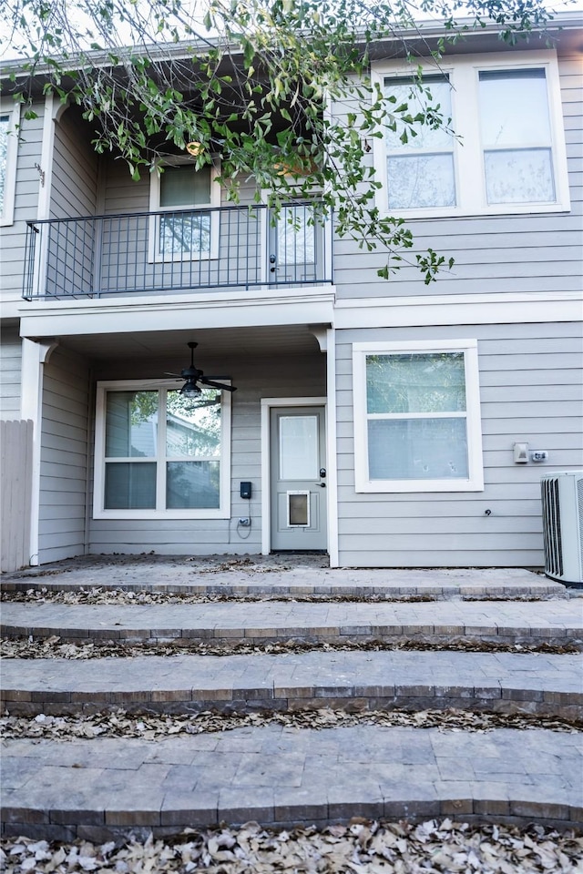 view of exterior entry featuring a ceiling fan and a balcony