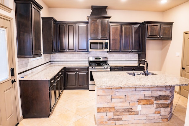 kitchen featuring appliances with stainless steel finishes, a sink, light stone counters, and tasteful backsplash