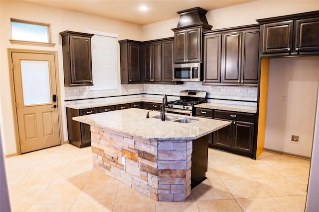 kitchen featuring light stone countertops, tasteful backsplash, appliances with stainless steel finishes, and a sink