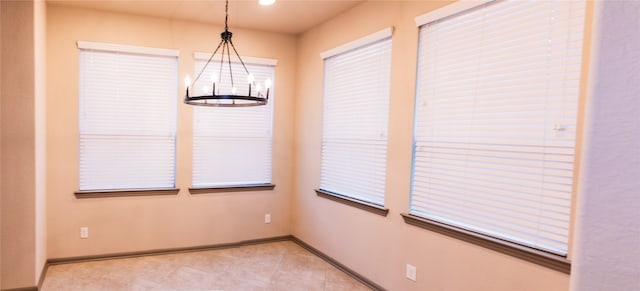 unfurnished room featuring light tile patterned floors, an inviting chandelier, and baseboards