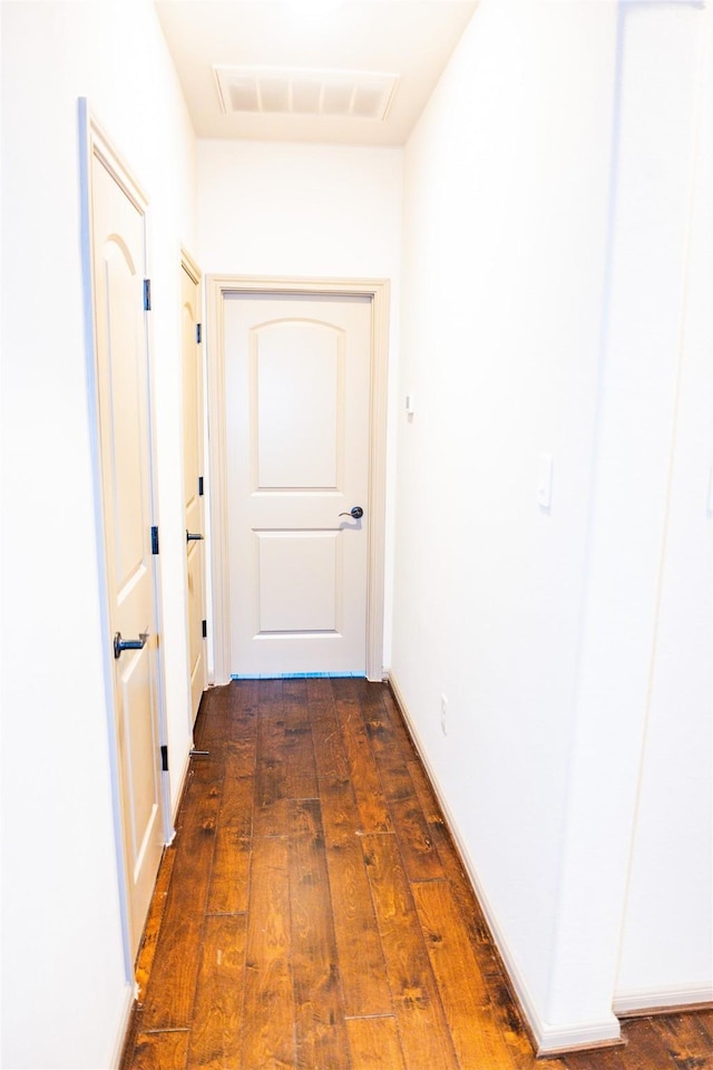 hallway featuring visible vents and dark wood-type flooring