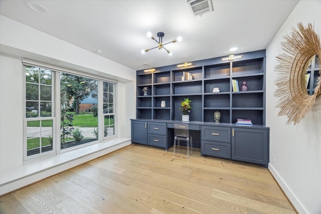 unfurnished office featuring visible vents, baseboards, baseboard heating, light wood-type flooring, and built in study area