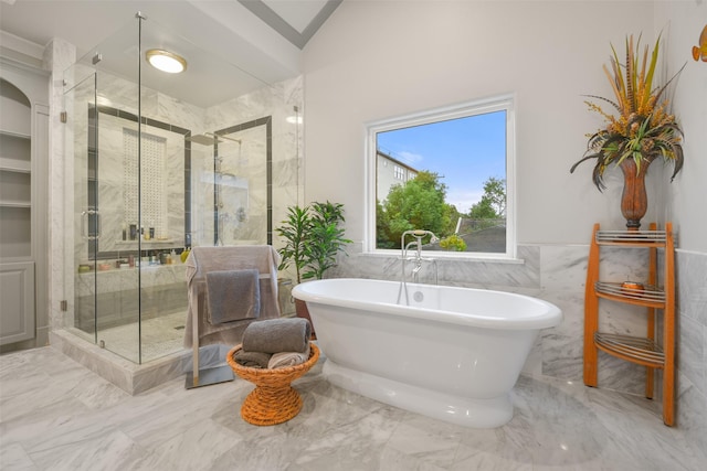 bathroom with a stall shower, lofted ceiling, a wainscoted wall, a soaking tub, and marble finish floor