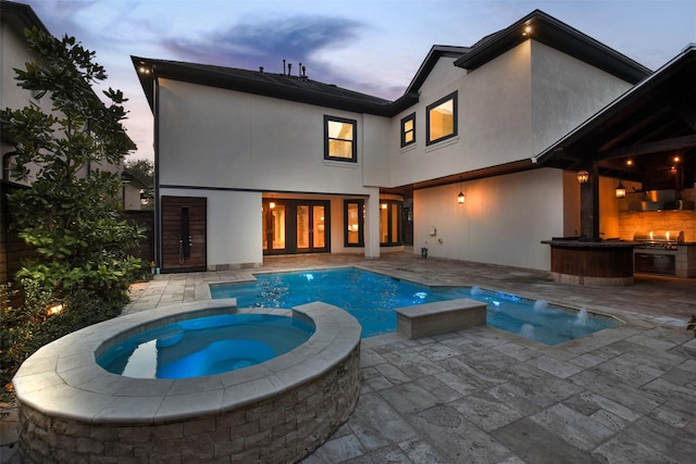 pool at dusk featuring a patio area and a pool with connected hot tub